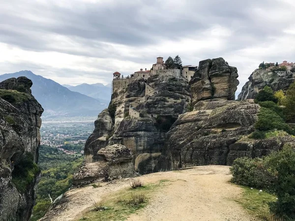 picturesque view of building on top of rock among mountains covered with forest at daytime