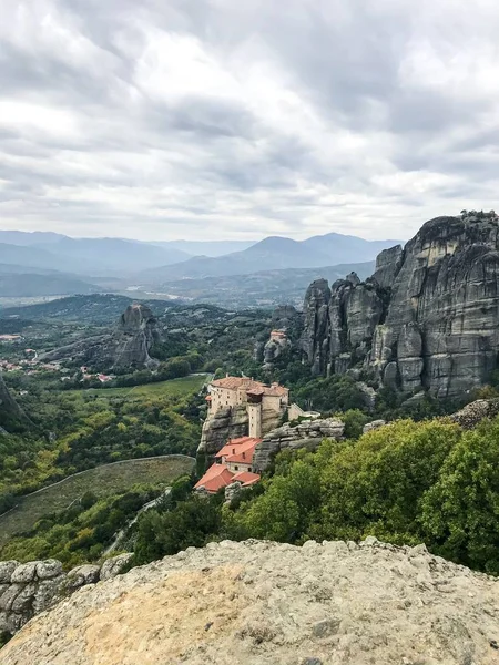 picturesque view of building on top of rock among mountains covered with forest at daytime