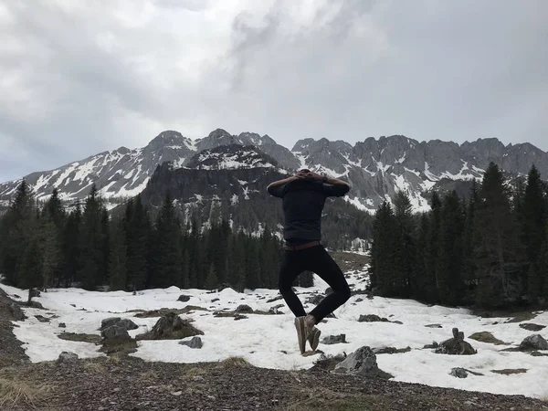 Visão Traseira Viajante Masculino Saltando Entre Montanhas Nevadas Cobertas Floresta — Fotografia de Stock