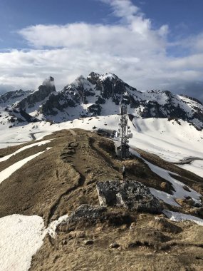 Güneşli bir günde tepesinde radyo kulesi olan karlı dağların resimli görüntüsü 