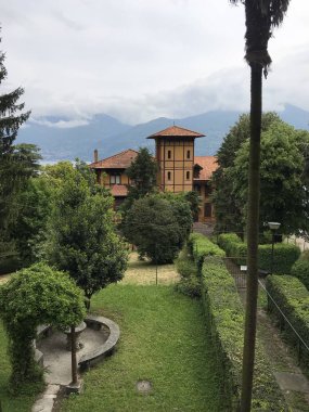 Güzel eski bina manzarası ve arkasında dağlar olan yeşil bahçe. 