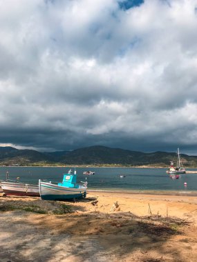 Gündüz vakti ormanla kaplı dağların arasında kıyıdaki ve göl manzaralı tekneler.  