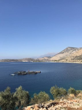 view of of offshore fish farm in sea among mountains at sunny day 