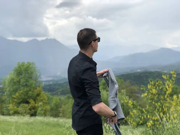 Όμορφος Άντρας Καθημερινά Ρούχα Κρατώντας Πουλόβερ Και Κοιτάζοντας Βουνά — Φωτογραφία Αρχείου