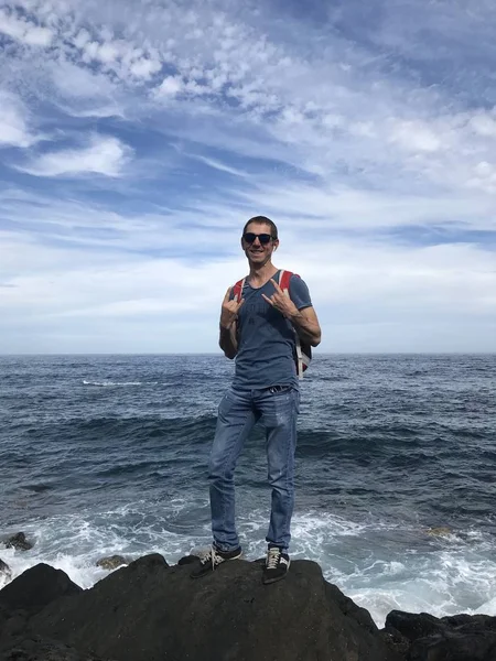 Man Solglasögon Med Ryggsäck Poserar Steniga Stranden Havet Sommardagen — Stockfoto