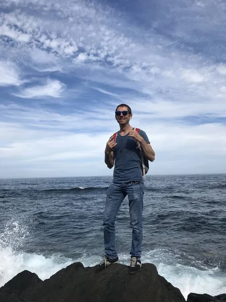 Man Solglasögon Med Ryggsäck Poserar Steniga Stranden Havet Sommardagen — Stockfoto