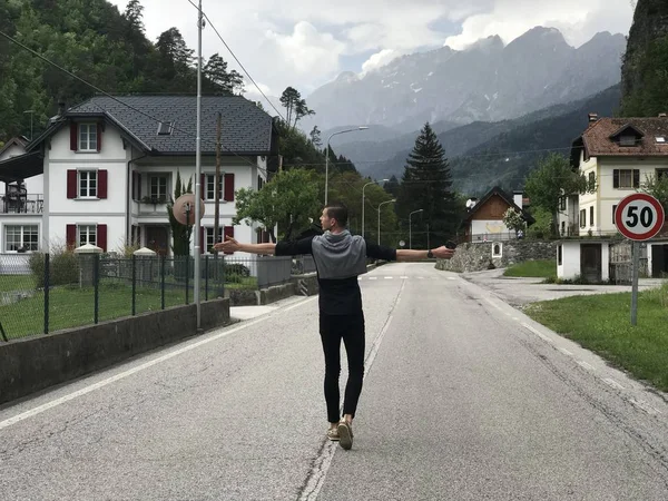 Visão Traseira Viajante Masculino Andando Estrada Vazia Aldeia Entre Montanhas — Fotografia de Stock