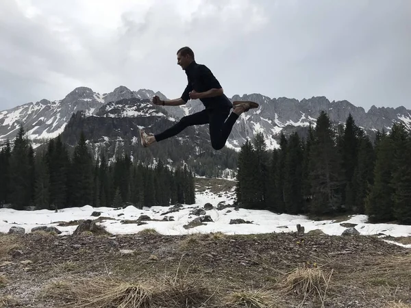 Visão Traseira Viajante Masculino Saltando Entre Montanhas Nevadas Cobertas Floresta — Fotografia de Stock