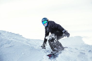 Kış giysileri içindeki adam, kış dağlarında, tepede snowboard yapıyor. 