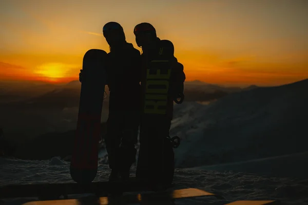 Pár Snowboardos Ölelkezik Miközben Hegyen Állnak Téli Hegyekben Napnyugtakor — Stock Fotó