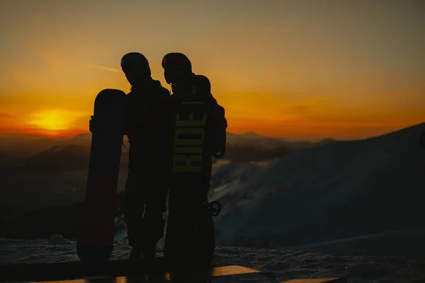 Pár Snowboardos Ölelkezik Miközben Hegyen Állnak Téli Hegyekben Napnyugtakor — Stock Fotó