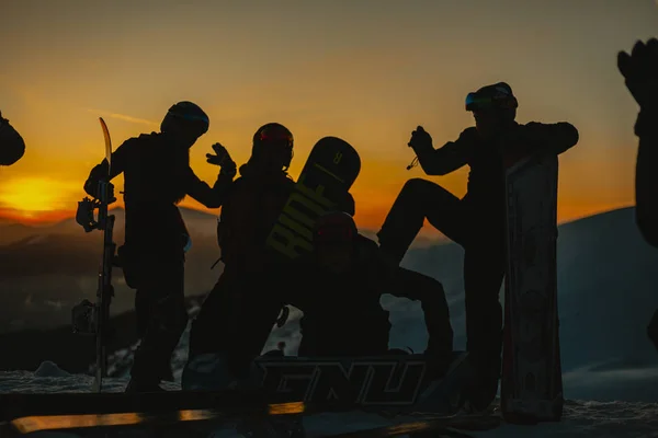 Sziluettek Snowboardosok Téli Ruhák Snowboardok Pihentető Dombon Télen Hegyek Naplementekor — Stock Fotó