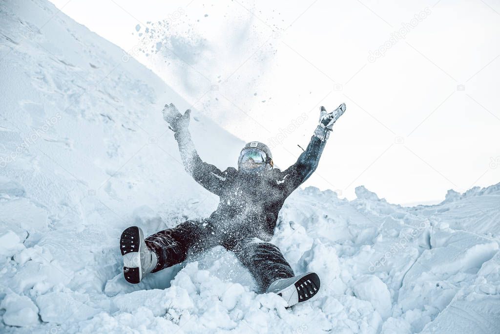 man in ski clothes falling on snow in winter mountains 