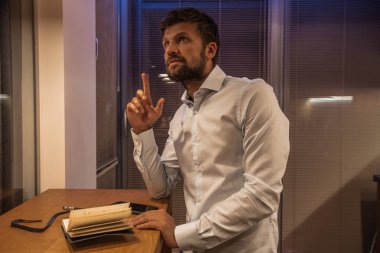 thoughtful bearded man in white shirt standing in kitchen 