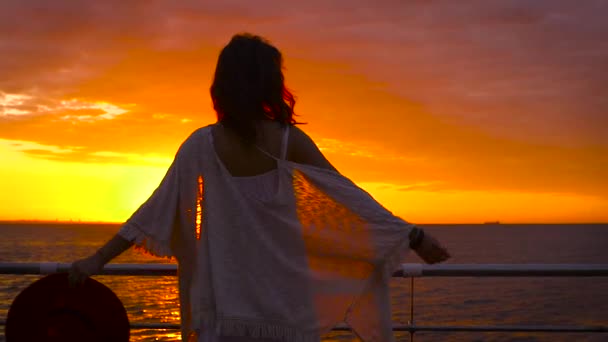 年轻漂亮的女人穿着白色的礼服和帽子摆在海上背景在惊人的日落 — 图库视频影像