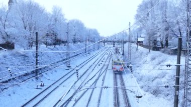 Banliyö yolcu treni karlı kış gününde kalkıyor.