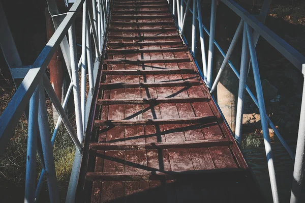 Tekneye indikleri suyun arka planında metal korkuluklu ahşap köprü. Yol, gezinti güvertesi..