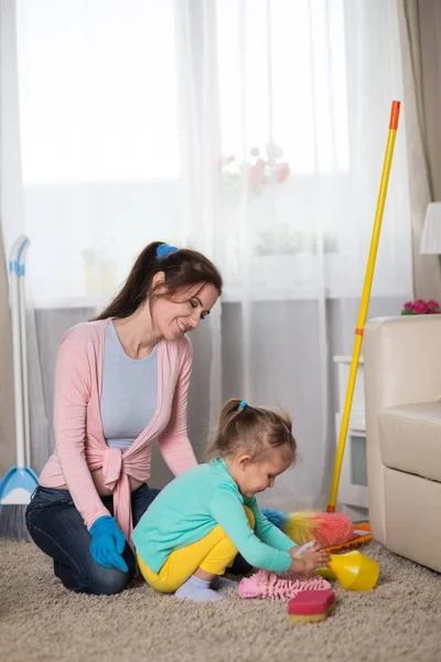 Mom and daughter are cleaning in the apartment, a woman and a girl of three years doing household chores