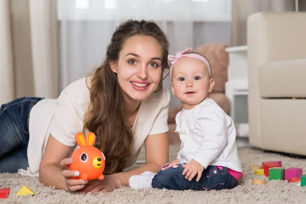 A young mother plays with a baby.