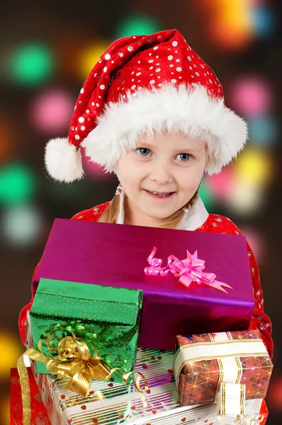 Happy Christmas kid in red hat with gifts — Stock Photo, Image