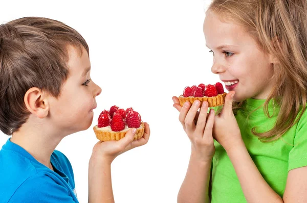 Little girl and boy eating cakes with fruits. — Stock Photo, Image