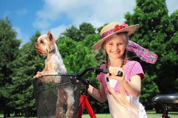 Portret van een klein meisje buitenshuis met fiets en hond. — Stockfoto