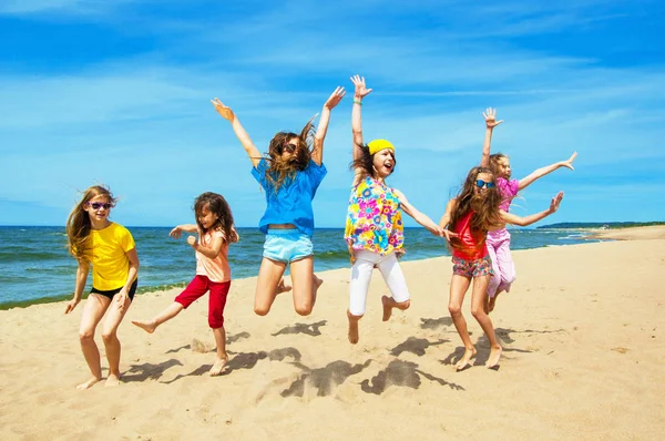 Crianças ativas felizes pulando na praia — Fotografia de Stock