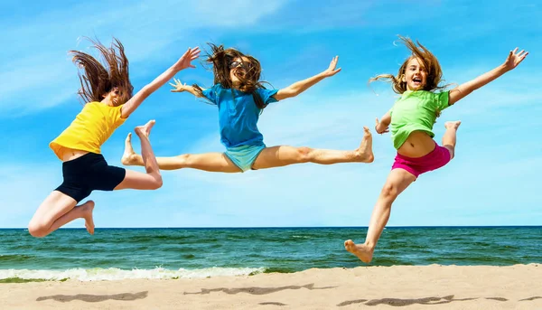 Happy active childrenl jumping at the beach — Stock Photo, Image