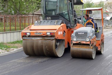 Gabrovo, Bulgaristan 13 Nisan 2018 sokak Asphalting. İki merdane asfalt düz. Büyük ve küçük silindir. İşçi konuşmak.