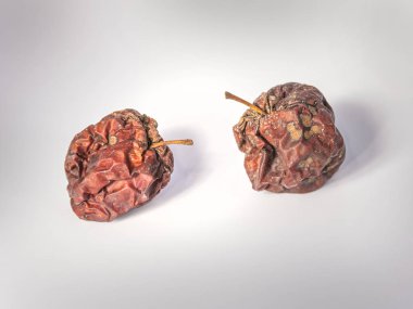 Parlak bir arka planda iki tane kurumuş elma. Buruşuk, kararmış ve çirkin. Yaşlılığın sembolleri.