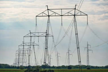 Olay yerinde yüksek voltajlı elektrik direkleri var. Aşağıdan vurulmuş. Gökyüzü arkaplan grafiği.