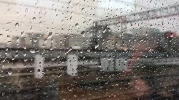 Vista a través del cristal de un vagón de tren a la calle en un día lluvioso. Gotas en el cristal de un tren en movimiento . — Vídeo de stock