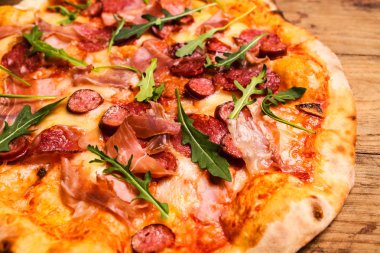 Sıcak pizza dilimi, erimiş peynirle ahşap bir masada..