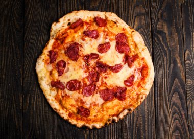 Sıcak pizza dilimi, erimiş peynirle ahşap bir masada..