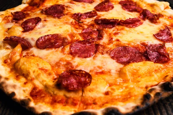 Hot pizza slice with melting cheese on a rustic wooden table. — Stock Photo, Image