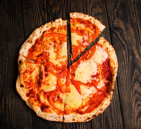 Hot pizza slice with melting cheese on a rustic wooden table. — Stock Photo, Image