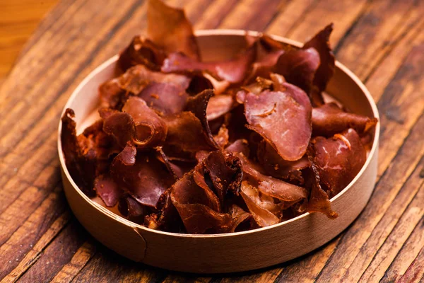 Rundvlees vlees plakjes gerookte over rustieke achtergrond — Stockfoto