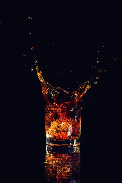 İzole kadeh viski siyah arka plan üzerinde sıçrama ile bir bardak brendi
