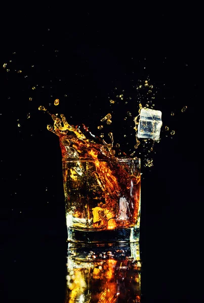 Isolated shot of whiskey with splash on black background, brandy in a glass