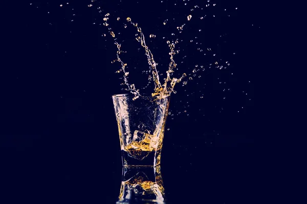 Isolated shot of whiskey with splash on black background, brandy in a glass