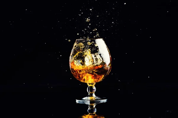 Glas Mit Cognac Mit Spritzer Auf Schwarzem Hintergrund — Stockfoto