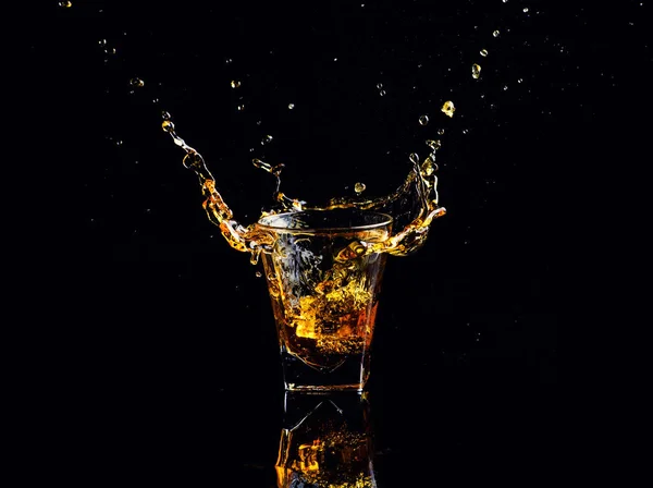 黒の背景にスプラッシュとウイスキーの分離ショット グラスにブランデーします — ストック写真