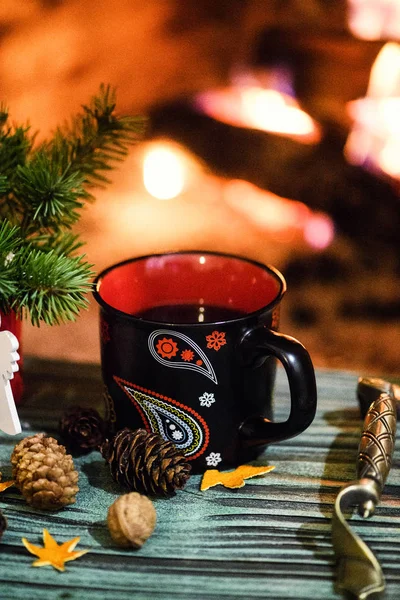 Christmas mulled wine in mugs with spices, on the background of a burning fireplace