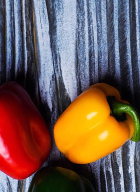 Ahşap arka plan üzerinde üç biber seti. Sarı, kırmızı ve yeşil biber.
