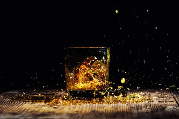 Elszigetelt lövés whisky fröccsenő fekete háttér — Stock Fotó