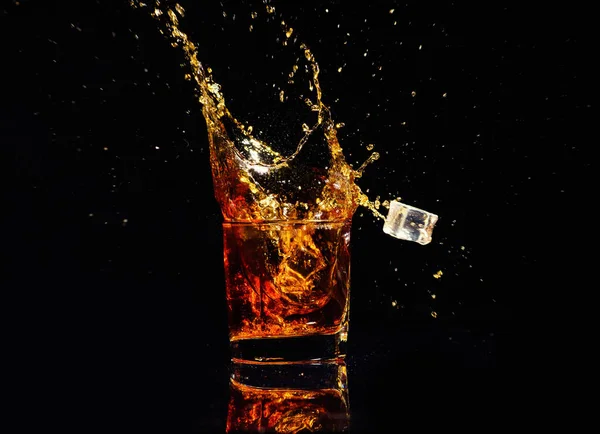 Geïsoleerde shot whisky met splash op zwarte achtergrond — Stockfoto