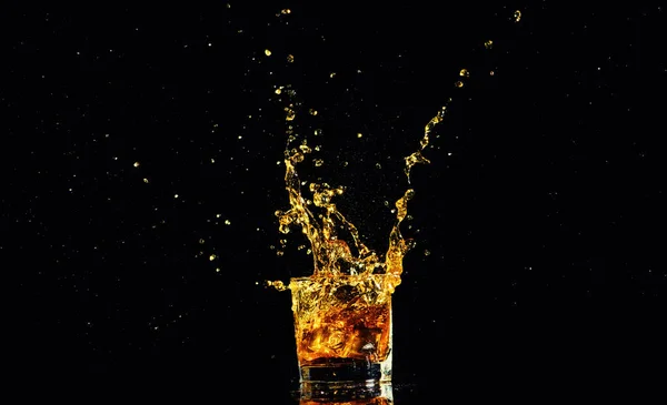 Tiro aislado de whisky con salpicadura sobre fondo negro —  Fotos de Stock