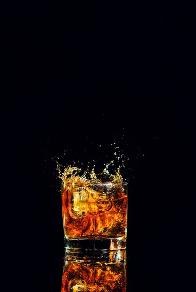 Tiro aislado de whisky con salpicadura sobre fondo negro — Foto de Stock