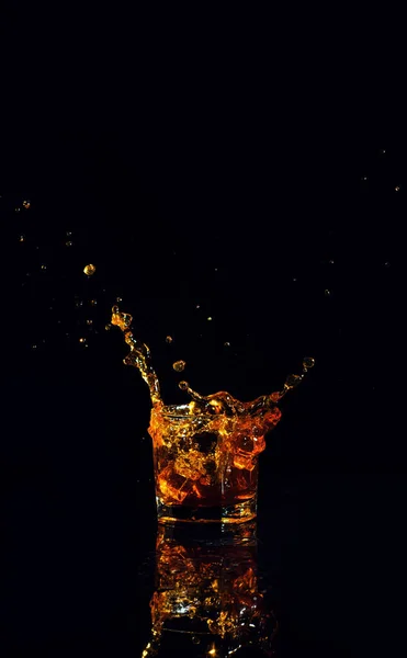 Elszigetelt lövés whisky fröccsenő fekete háttér — Stock Fotó