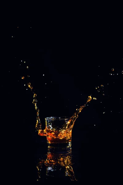 Geïsoleerde shot whisky met splash op zwarte achtergrond — Stockfoto